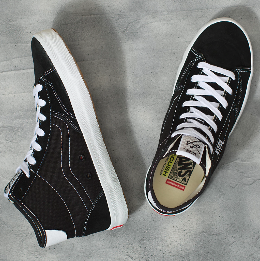A pair of VANS THE LIZZIE BLACK / WHITE shoes on a cement floor.