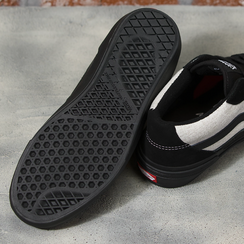 A pair of VANS BMX Style 114 Fast and Loose black shoes sitting on top of a cement floor.