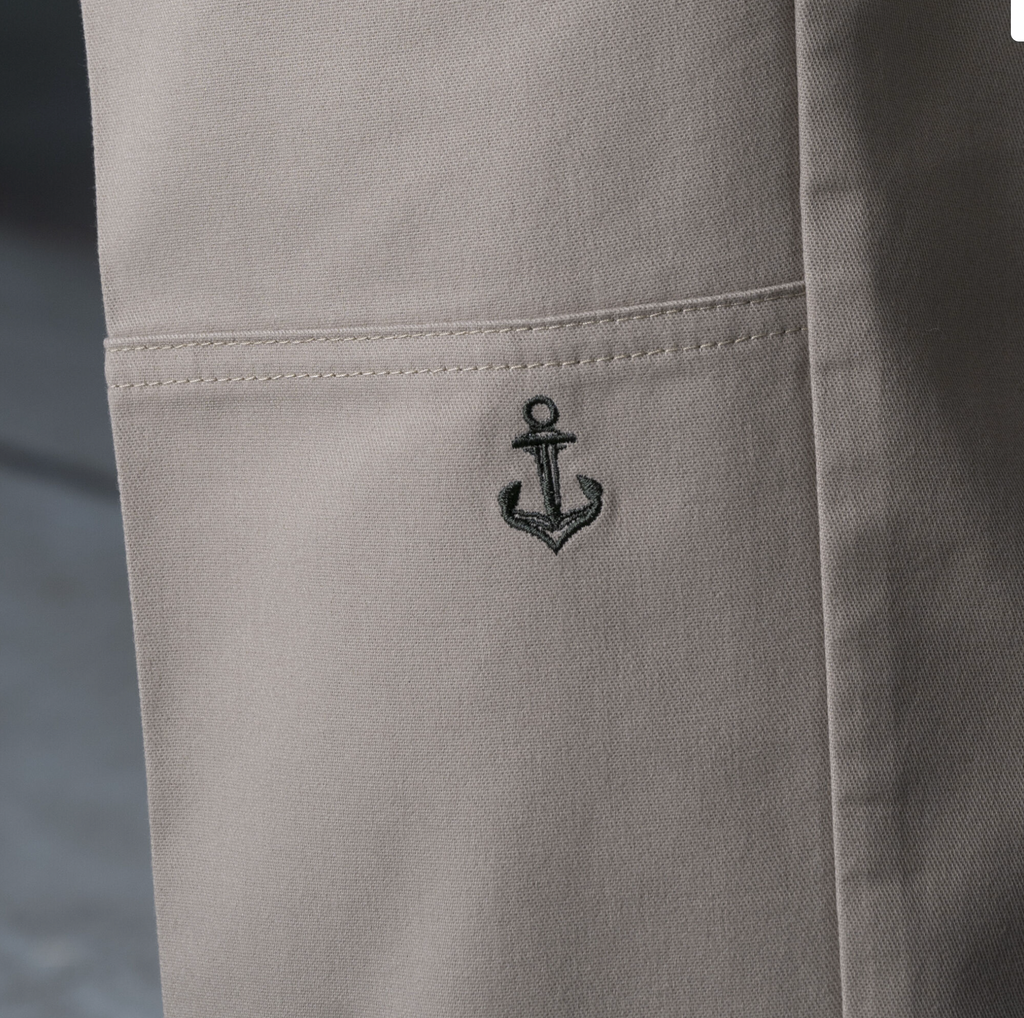A close up of a person's Dickies Ronnie Sandoval Double Knee Pant Desert Sand/Olive with an anchor embroidered on the side.