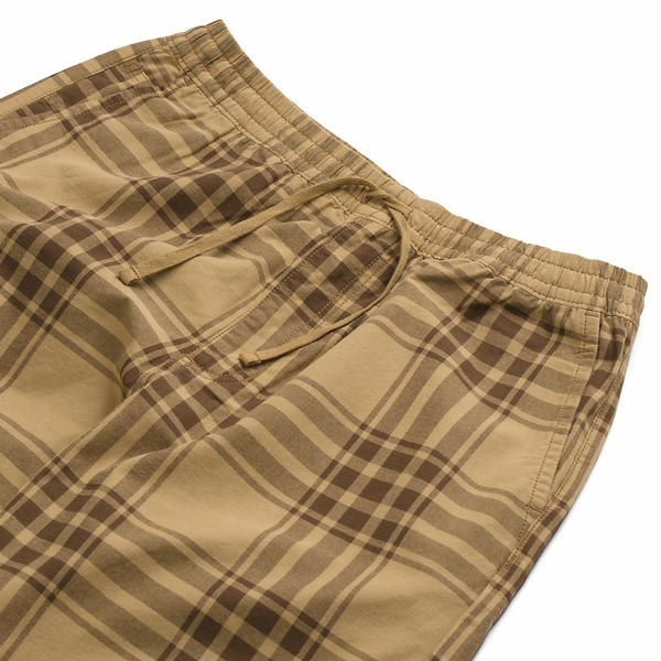 A close up of VANS RANGE PLAID BAGGY TAPERED ELASTIC WAIST PANT BROWN on a white surface.
