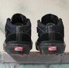 A pair of black and red VANS SKATE HALF CAB GORE-TEX BLACK high tops sitting on a brick wall.