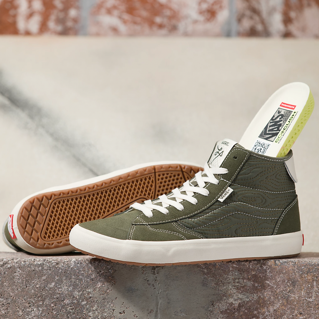 A pair of VANS THE LIZZIE QUILTED GRAPE LEAF sneakers sitting on top of a cement wall.