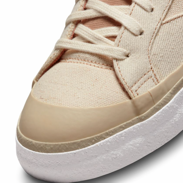 A pair of Nike beige sneakers with white soles.
