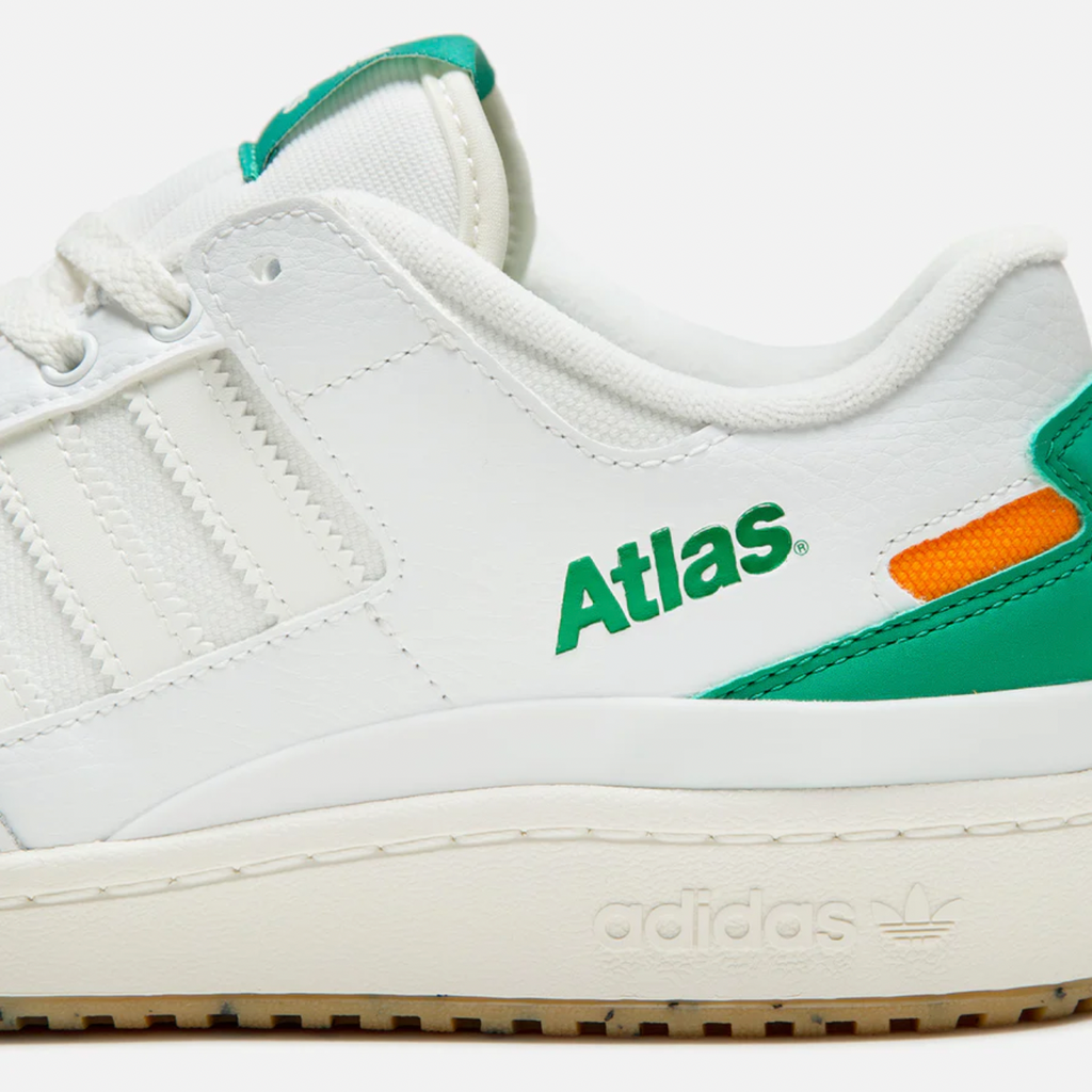 A white and green ADIDAS X ATLAS FORUM 84 LOW ADV sneaker with the word atlas on it.