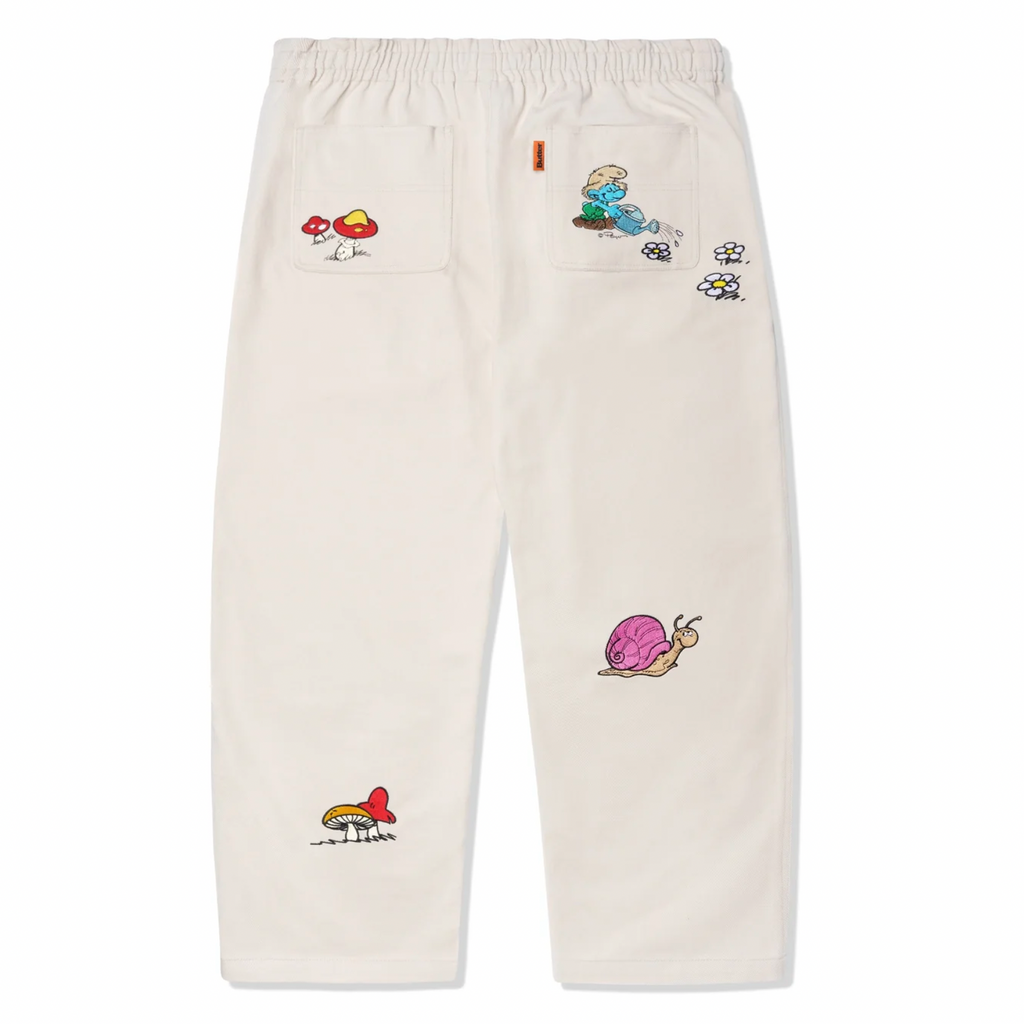 A pair of BUTTER GOODS X THE SMURFS FORAGE WIDE LEG PANT NATURAL with patches on them.