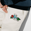 A close up of a person's Butter Goods Forage wide leg pant in natural with The Smurfs cartoon character on it.