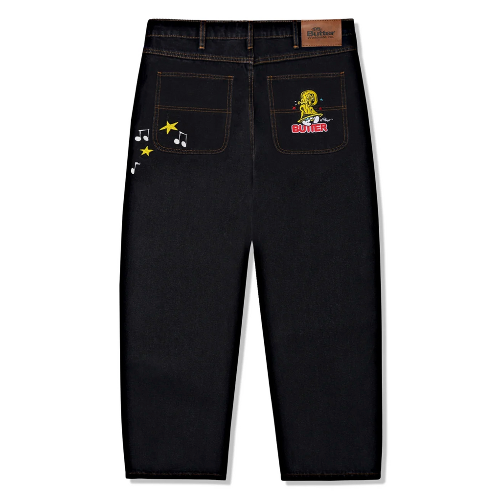 A pair of BUTTER GOODS X THE SMURFS HARMONY DENIM PANTS with patches on them.