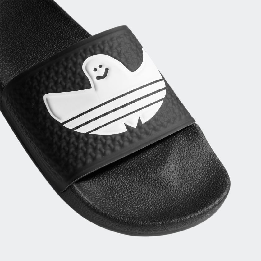 An ADIDAS SHMOOFOIL SLIDE CORE BLACK / WHITE with a white ghost on it.