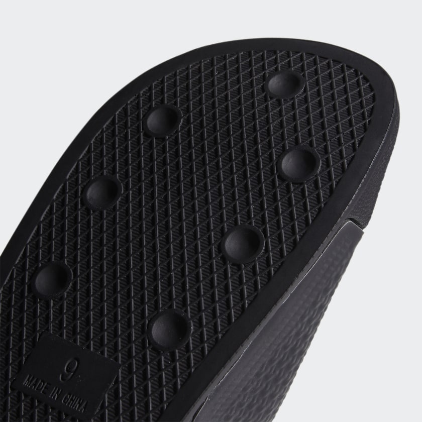 A close up of the sole of an ADIDAS SHMOOFOIL SLIDE CORE BLACK / WHITE.