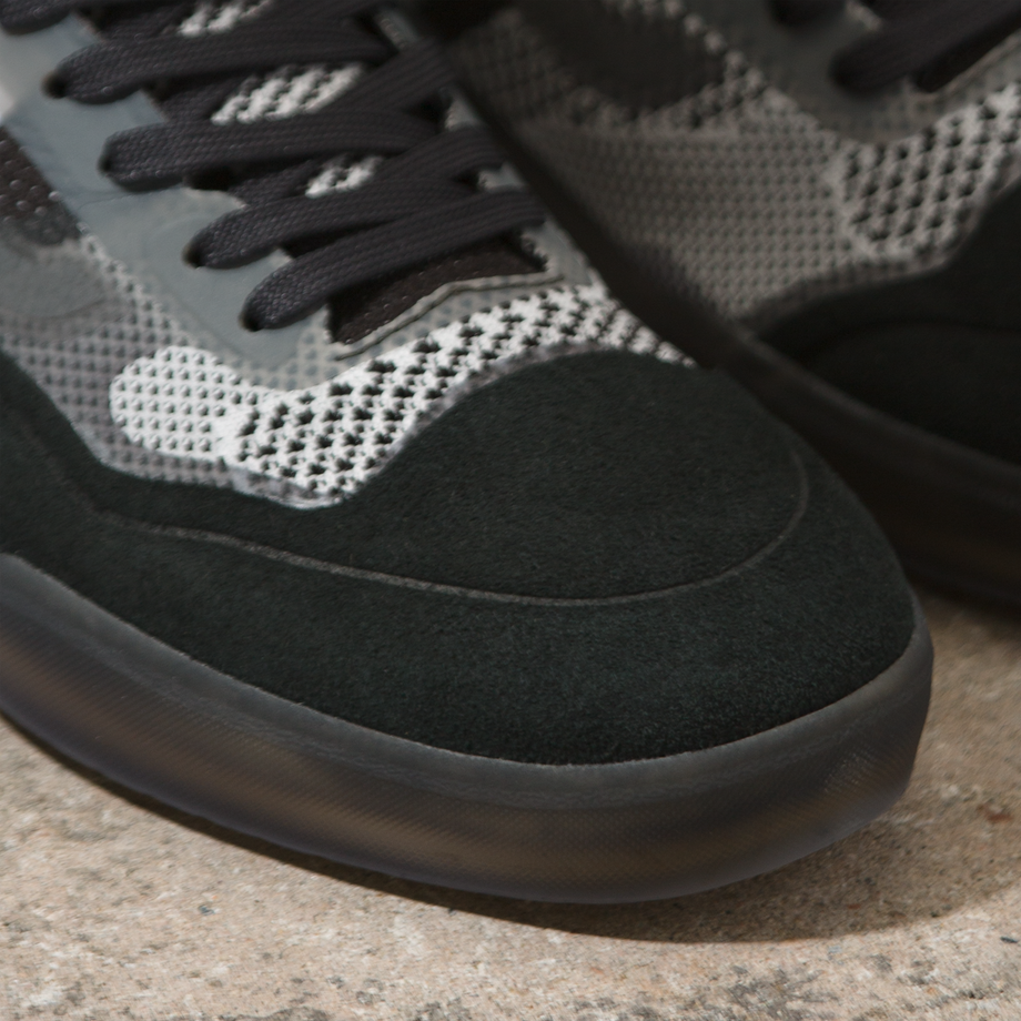 A pair of VANS AVE KNIT VCU BLACK/WHITE/FLECK sneakers on a cement surface.