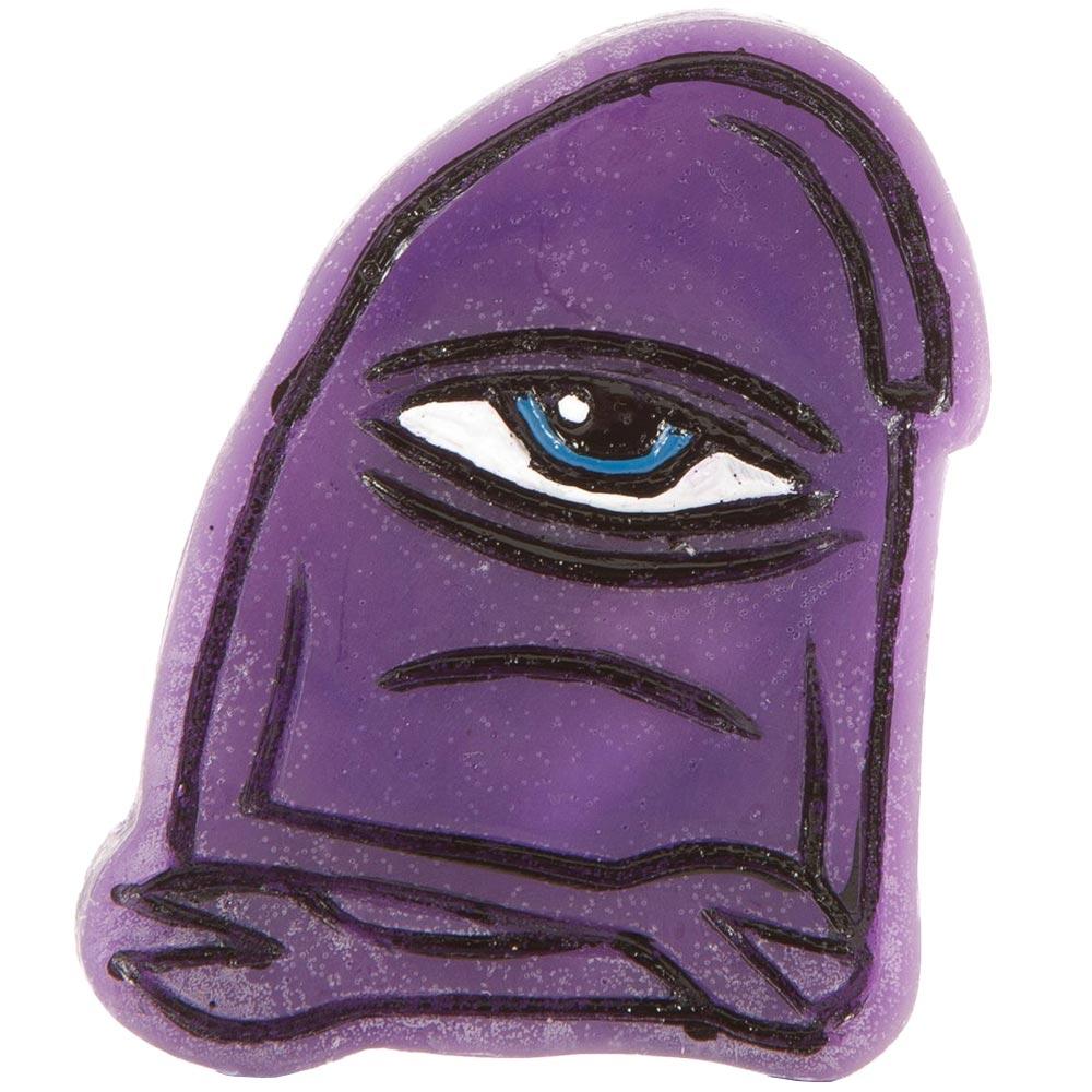 A TOY MACHINE TRANSMISSIONATOR WAX PURPLE with a cartoon face featuring one eye, a heavy eyelid, and a slightly frowning mouth from Toy Machine.