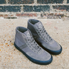 A pair of grey VANS CROCKETT HIGH BUNGEE CORD / BLACK sneakers sitting on a brick wall.