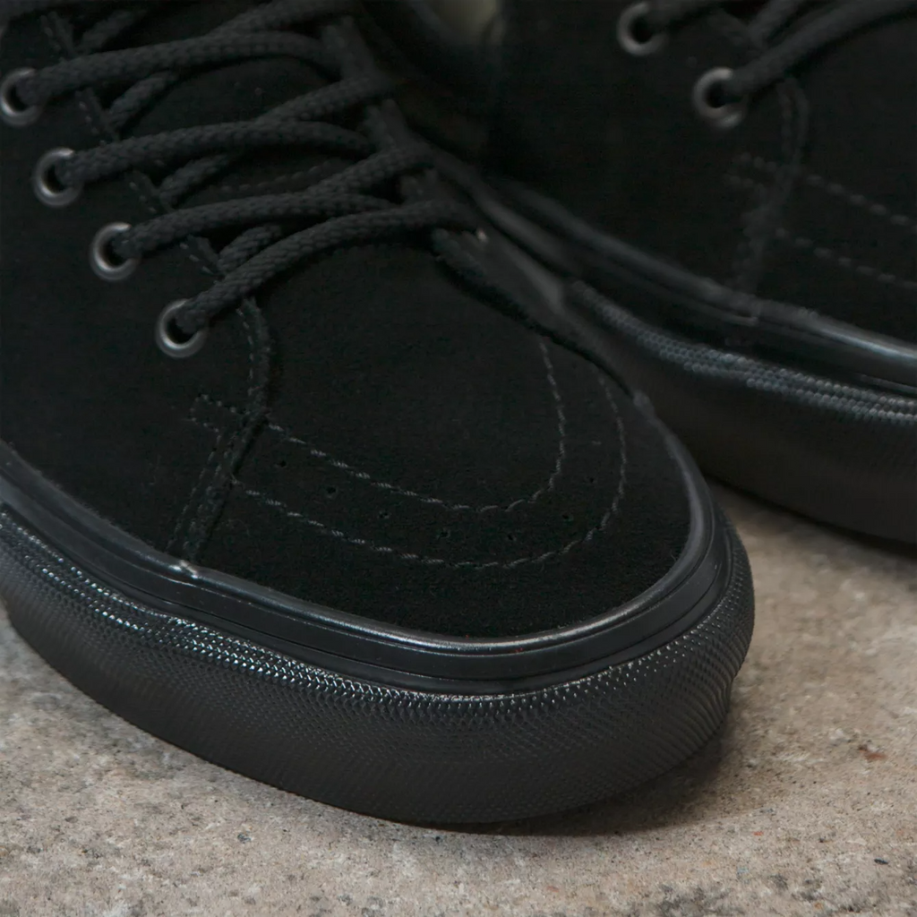 A pair of black VANS KADOW SKATE SK8-Hi WEB sneakers on a concrete floor.