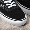 A pair of VANS SKATE ERA BLACK / WHITE shoes sitting on top of a stone floor.