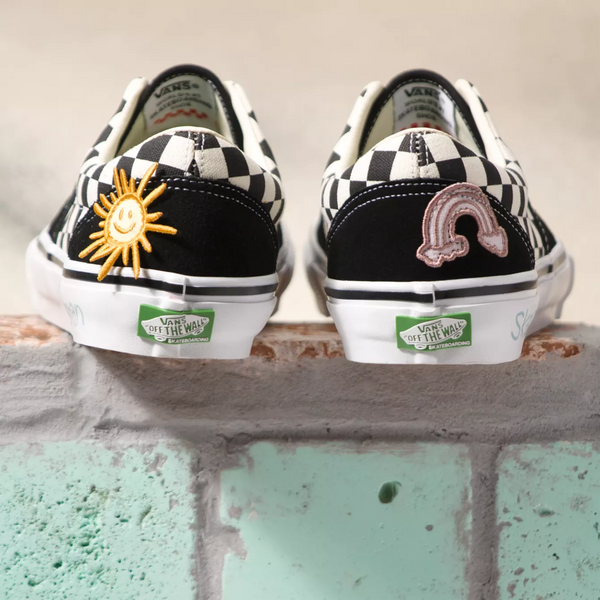 the back of checkered and black shoes with colorful patches sitting on a wall