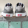 A pair of grey and white VANS SKATE WAYVEE sneakers on a brick wall.