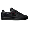 A pair of black ADIDAS x GONZ SUPERSTAR ADV CORE BLACK / BLACK / BLACK sneakers with a bird on them.