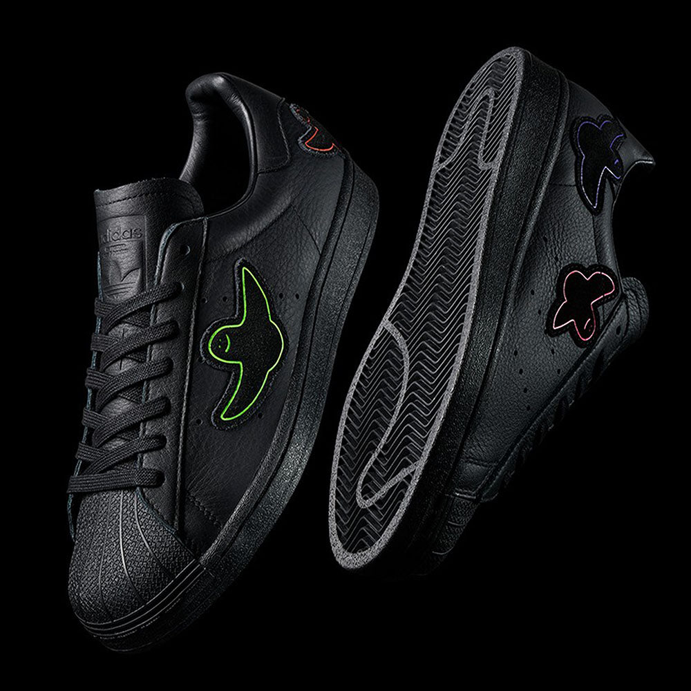 A pair of ADIDAS x GONZ SUPERSTAR ADV CORE BLACK / BLACK / BLACK sneakers with a bird on them from ADIDAS.