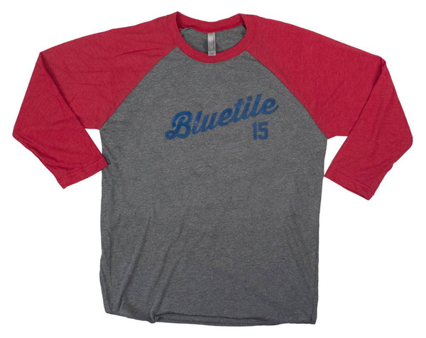 A gray and red BLUETILE 15 YEARS RAGLAN (GLOW IN THE DARK) tee with the word Bluetile Skateboards on it.