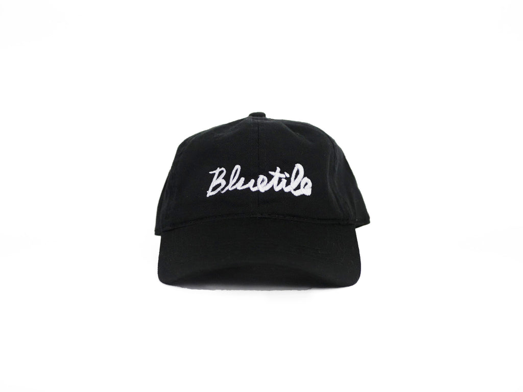 A BLUETILE CURSIVE DAD HAT BLACK with white lettering on it from Bluetile Skateboards.