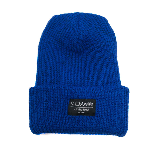 A BLUETILE SURPLUS KNIT BEANIE ROYAL BLUE with a black label on it, perfect for adding a touch of style to any outfit. (Brand Name: Bluetile Skateboards)