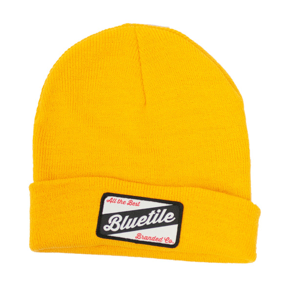 A yellow BLUETILE CRAFT PATCH BEANIE GOLD with a Bluetile Skateboards patch on it.
