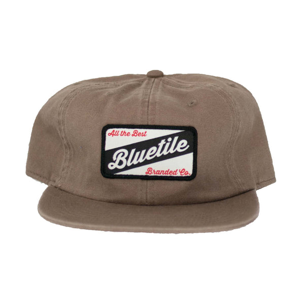 A brown BLUETILE CRAFT PATCH HAT COFFEE with a patch on the front showcasing the Bluetile Skateboards logo.