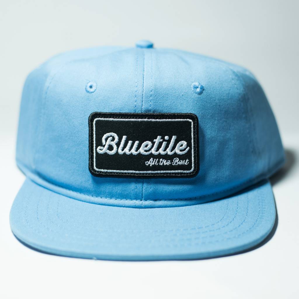 A blue hat with a BLUETILE "ALL THE BEST" PATCH CAROLINA BLUE on it, representing Bluetile Skateboards.