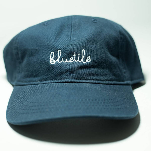 A BLUETILE SCRIPT DAD HAT NAVY with the word 'bluetle' embroidered on it, by Bluetile Skateboards.