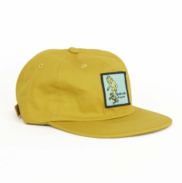 A Bluetile Sketchy Patch Hat Maize with a blue patch on it.
