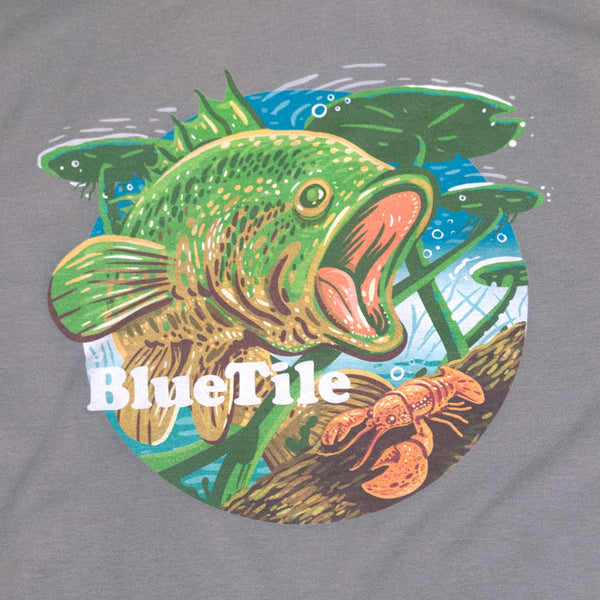 A Bluetile Skateboards Wilderness Bass T-Shirt Concrete with an image of a fish and a crawfish in the wilderness.