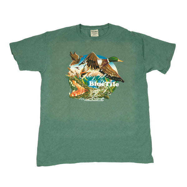 A BLUETILE WILDERNESS DUCKS T-SHIRT CYPRESS GREEN from Bluetile Skateboards, with an image of a duck and a crocodile, perfect for Bluetile Skateboards Wilderness Ducks enthusiasts.