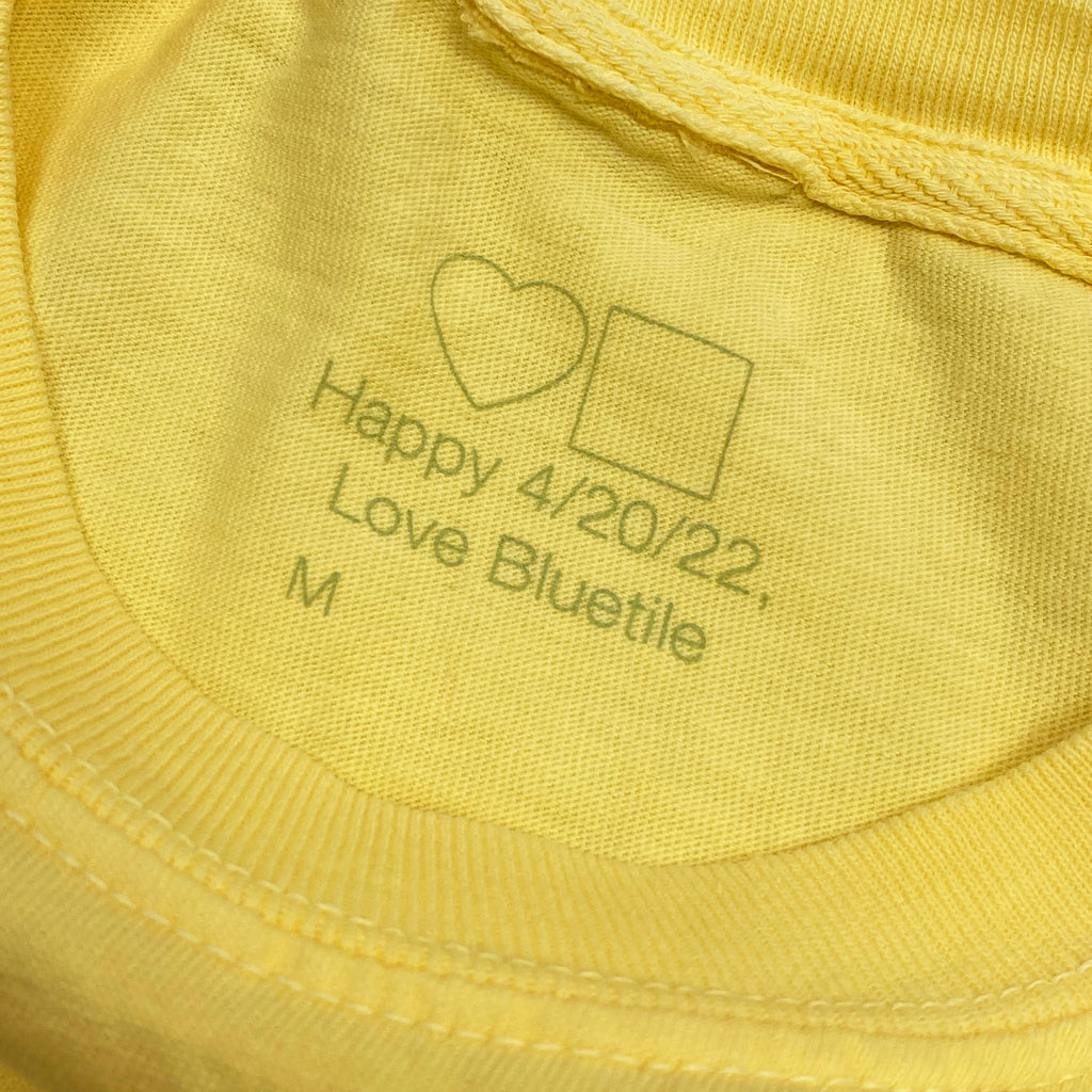 A yellow BLUETILE GARDEN CLUB TEE BUTTER with the words love Bluetile Skateboards on it.