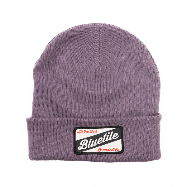 A BLUETILE CRAFT PATCH BEANIE MAUVE with a Bluetile Skateboards patch on it.