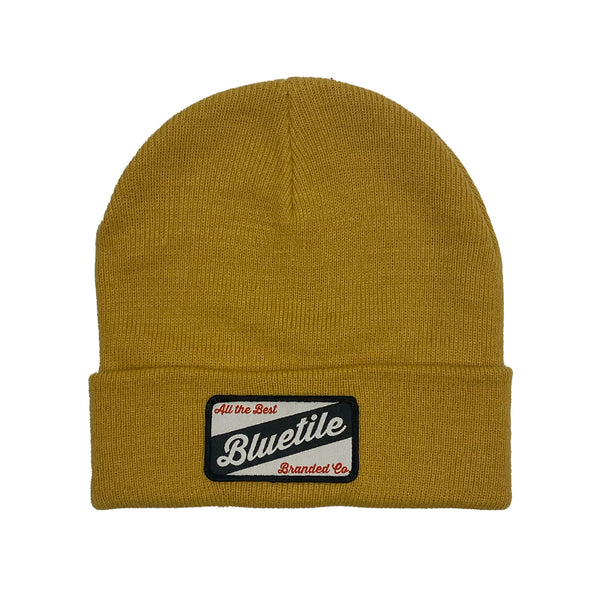 A yellow BLUETILE CRAFT PATCH BEANIE MUSTARD with a bluebelle patch from Bluetile Skateboards.