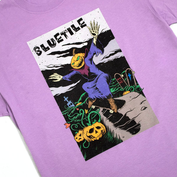 A BLUETILE DEATH RACE TEE PURPLE with an image of a skeleton riding a pumpkin.