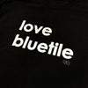 A Bluetile Skateboards black t-shirt with the word love Bluetile on it.