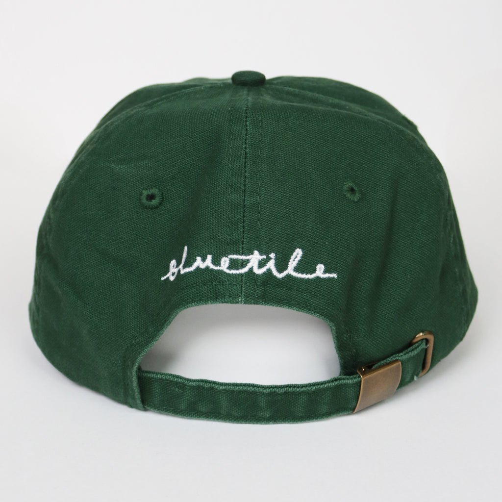 A BLUETILE X SPINA HEART & SQUARE HAT GREEN with the word schuttle written on it. Brand Name: Bluetile Skateboards