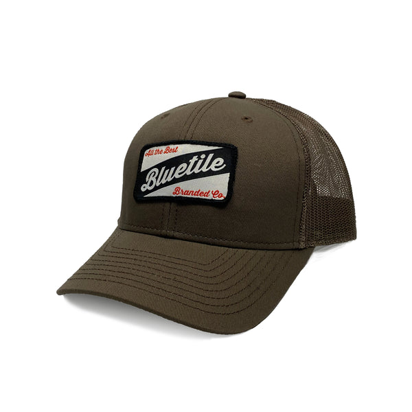 A Bluetile Skateboards BLUETILE CRAFT PATCH TRUCKER WALNUT hat with a patch on it.