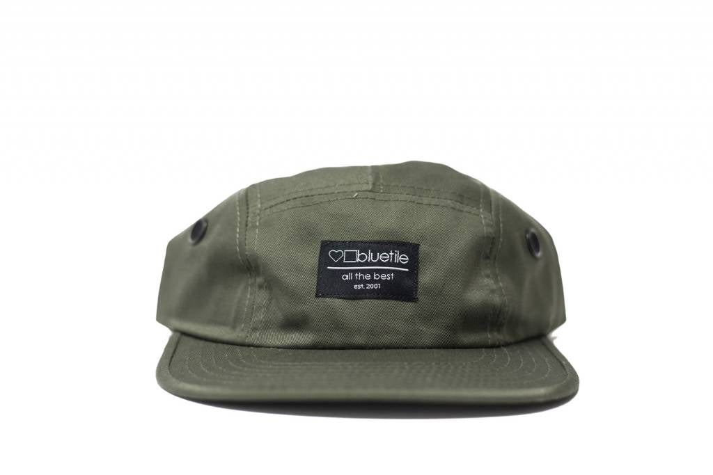 A Bluetile Skateboards BLUETILE SURPLUS 5 PANEL HAT OLIVE GREEN with a black patch on it.