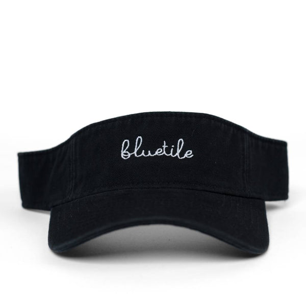 A BLUETILE SCRIPT VISOR BLACK with the word 'blush' embroidered on it, perfect for staying protected from the sun while looking fashionable, made by Bluetile Skateboards.