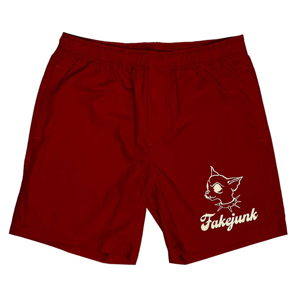 FAKE JUNK CHI CHI BEACH SHORTS in red, designed with an elastic waistband and side pockets, featuring a cat graphic and the words "FakeJunk" printed in white on one leg.