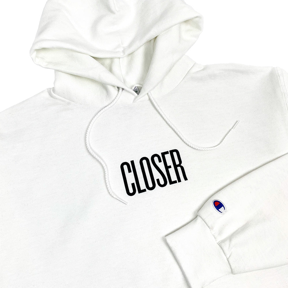 A close up of a CLOSER MAG HOODIE WHITE with the word CLOSER on it.