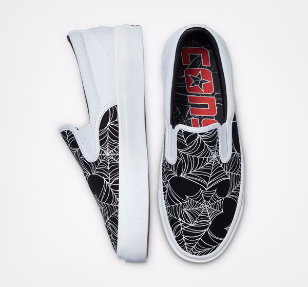 A pair of black and white slip-on shoes with spider webs on them, inspired by the CONVERSE CONS ONE STAR CC SLIP WHITE / BLACK / WHITE collection from CONVERSE.