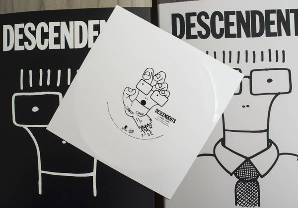 Three Descendents music albums with cartoon covers are arranged. The SANTA CRUZ X DESCENDENTS MILO GOES TO COLLEGE skateboard deck, featuring a white vinyl design with a cartoon hand holding dice in the center, is placed on top.