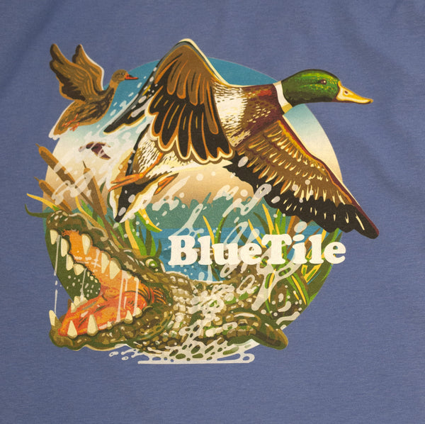A Bluetile Skateboards BLUETILE WILDERNESS DUCKS T-SHIRT FORTE BLUE with a duck and crocodile on it.
