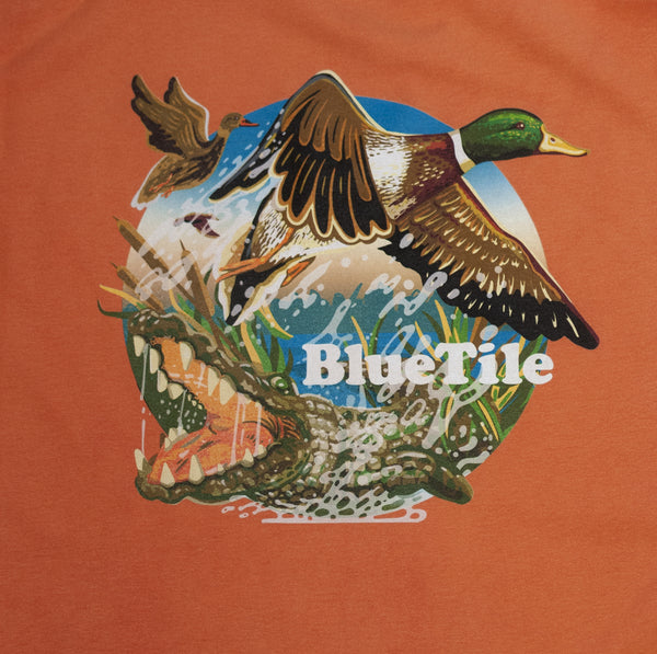 A BLUETILE WILDERNESS DUCKS LONG SLEEVE HORIZON t-shirt featuring an image of a duck and a crocodile on an orange background. (Brand Name: Bluetile Skateboards)