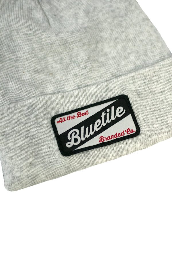A BLUETILE CRAFT PATCH BEANIE HEATHER WHITE with a blue patch on it by Bluetile Skateboards.