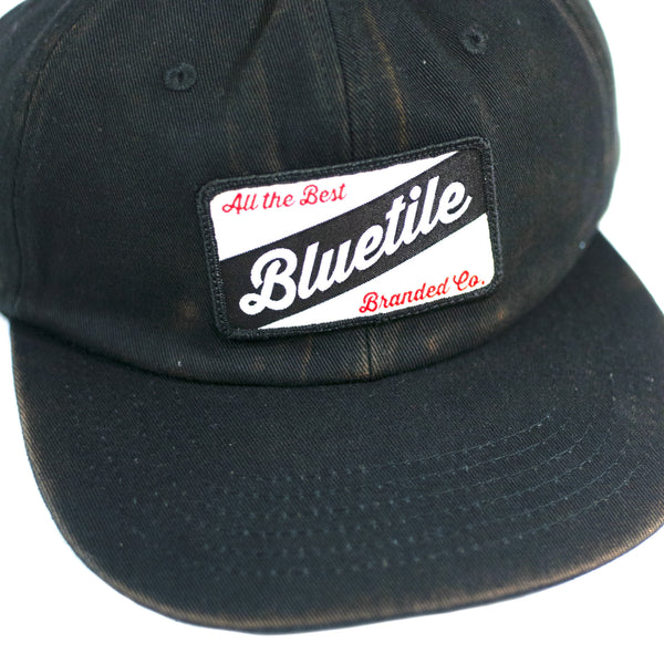 A BLUETILE CRAFT PATCH HAT FADED BLACK with a CRAFT PATCH that says BLUETLE made by Bluetile Skateboards.