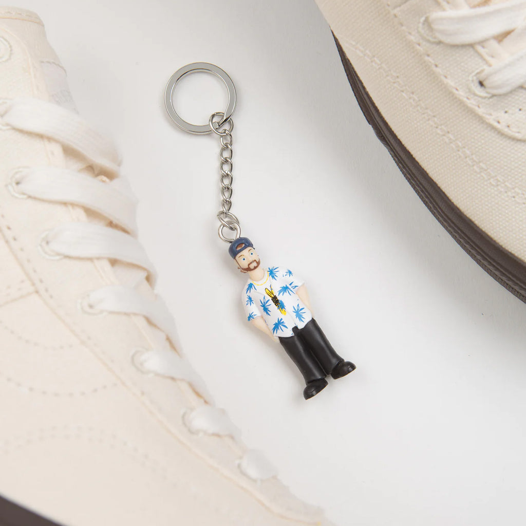 a pair of VANS SKATE X QUASI CROCKETT HIGH DECON WHITE shoes and a keychain with a toy soldier on it.